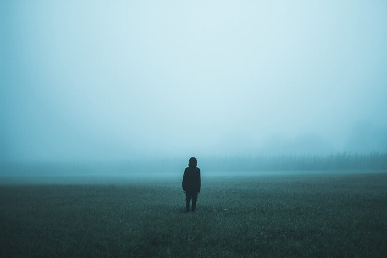 Person står på dimmigt fält.